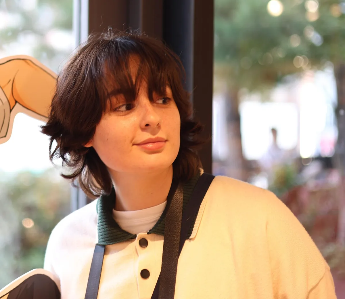 Noa Shaish, looking to the side, in a cream cardigan